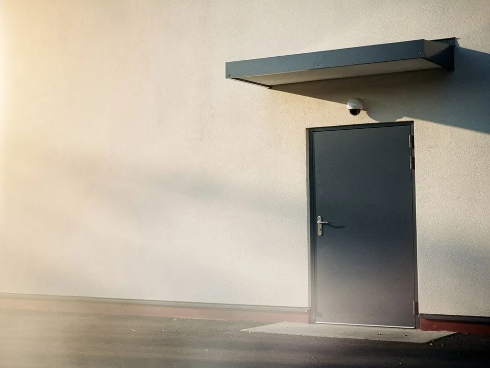 Secure building entrance with a closed steel door and a camera dome